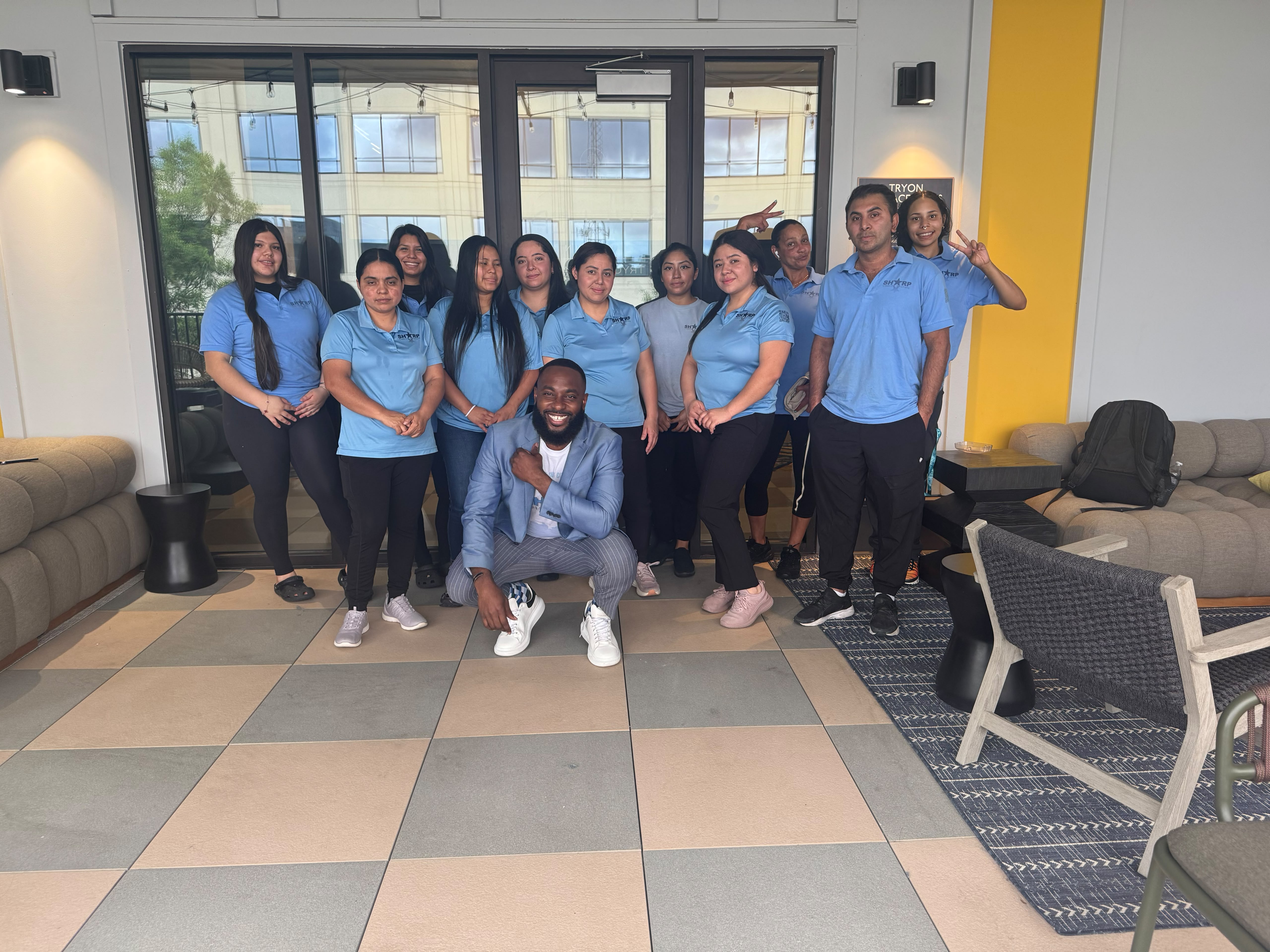 The Sharp Cleaning Solutions crew with Cornell Lewis in a modern commercial lobby